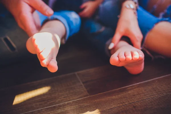 Adultos padres manos sosteniendo pequeños pies de bebé — Foto de Stock