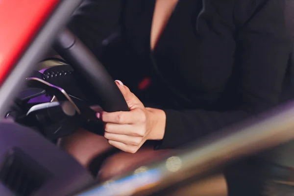 Lang vrouwelijke benen op een stuurwiel van een auto. — Stockfoto