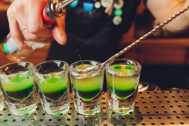 Barmen rom ve likörle alkollü shot yapar..