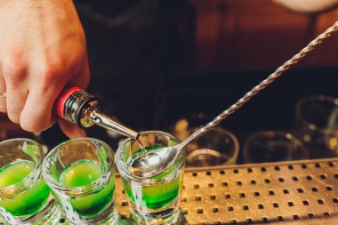 Barmen rom ve likörle alkollü shot yapar..