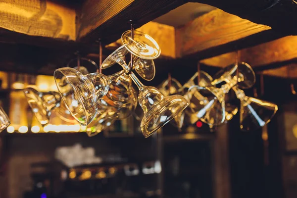 Ομάδα άδειο γυαλιά κρασιού που κρέμονται από μεταλλικές δοκοί σε ένα μπαρ. — Φωτογραφία Αρχείου