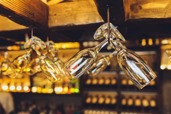 Grupo de copos de vinho vazios pendurados em vigas de metal em um bar . — Fotografia de Stock