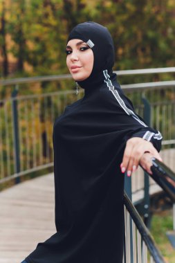 Sabahın erken saatlerinde yürüyüş köprüsünde egzersiz yapan tesettürlü kız. Spor kıyafetleri giyen Müslüman bir kadın dışarıda egzersiz yapıyor..