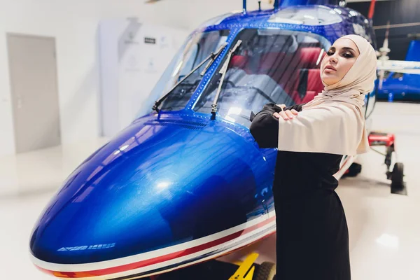 Elegante mujer árabe musulmana de negocios cerca del helicóptero. Negocios, éxito y concepto de lujo. hangar helicóptero — Foto de Stock