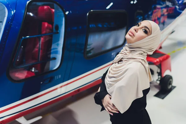 Elegante mujer árabe musulmana de negocios cerca del helicóptero. Negocios, éxito y concepto de lujo. hangar helicóptero — Foto de Stock