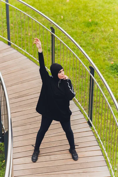 Chica Hijab haciendo ejercicio en el puente de la pasarela temprano en la mañana. Mujer musulmana usando ropa deportiva haciendo ejercicio de estiramiento al aire libre . — Foto de Stock