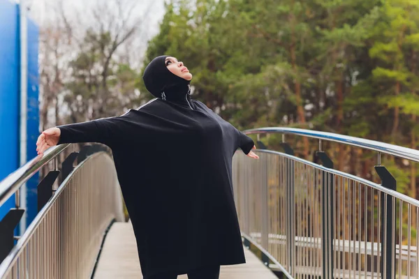 Chica Hijab haciendo ejercicio en el puente de la pasarela temprano en la mañana. Mujer musulmana usando ropa deportiva haciendo ejercicio de estiramiento al aire libre . — Foto de Stock