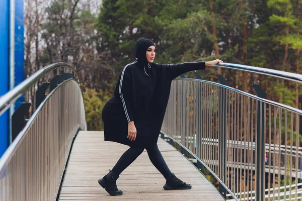 Hijab meisje traint op walkway bridge in de vroege ochtend. Moslim vrouw draagt sport kleding doen stretching workout buiten. — Stockfoto