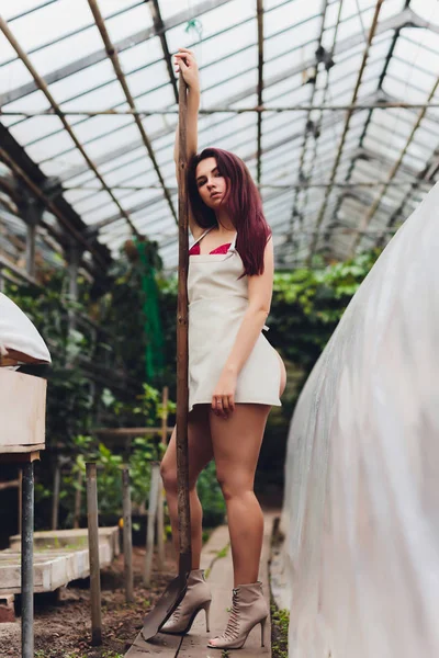 Pretty young woman gardening in an apron, without clothes. — ストック写真