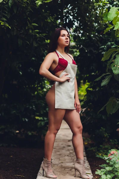 Jovem bonita jardinagem em um avental, sem roupas . — Fotografia de Stock