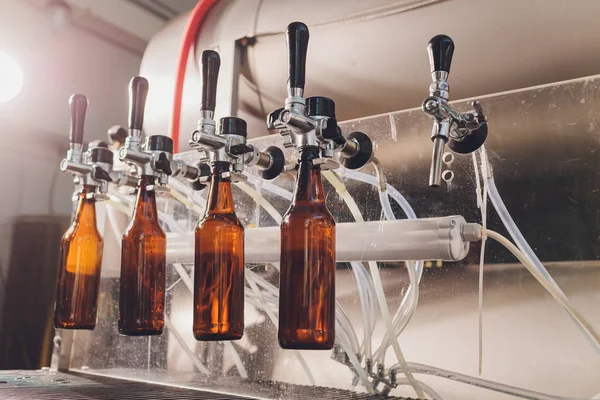 Fábrica de cerveza derramando cerveza en botellas de vidrio en líneas transportadoras. Trabajos industriales, producción automatizada de alimentos y bebidas. Trabajos tecnológicos en la fábrica . — Foto de Stock