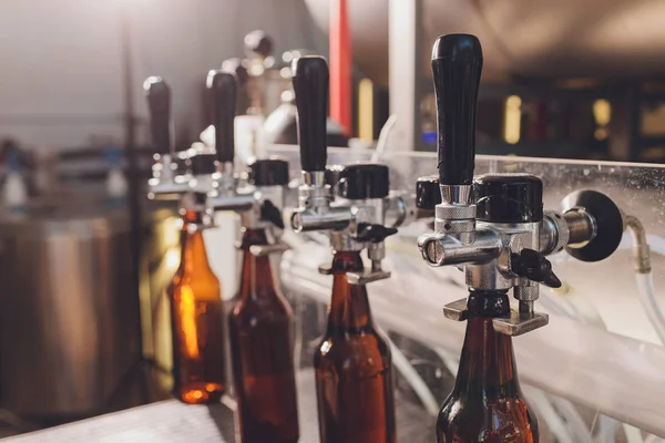 Pabrik pembuatan bir tumpah ke botol kaca pada baris konveyor. Kerja industri, produksi otomatis makanan dan minuman. Teknologis bekerja di pabrik . — Stok Foto