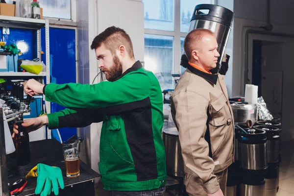 Fábrica de cerveza derramando cerveza en botellas de vidrio en líneas transportadoras. Trabajos industriales, producción automatizada de alimentos y bebidas. Trabajos tecnológicos en la fábrica . — Foto de Stock