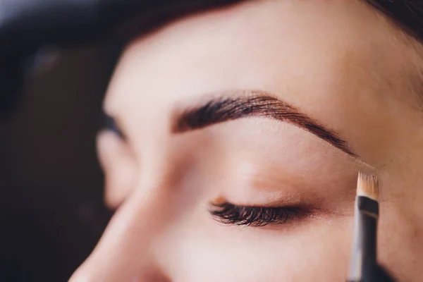 Esthéticienne maquilleuse applique de la peinture au henné sur des sourcils préalablement arrachés, design, taillés dans un salon de beauté lors de la correction de session. Soins professionnels pour le visage. — Photo