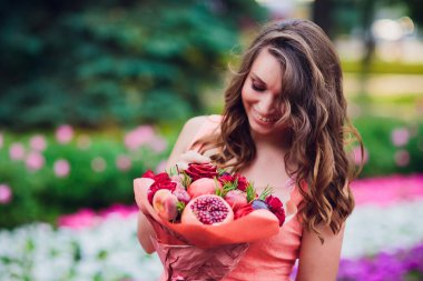 Meyve ve böğürtlen çeşitleri. Meyveli genç bayan elinde buket tutuyor..