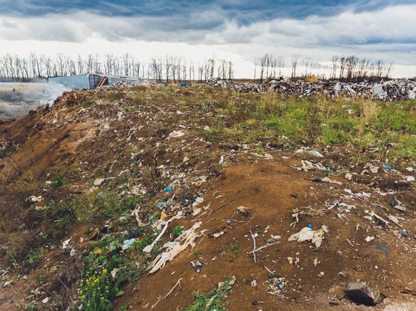 La grande décharge tas d'ordures s'étend parallèlement à la rivière, les montagnes d'ordures avec ciel nuageux fond de terre à la lumière du jour, les déchets ont des produits pétroliers sont les principaux . — Photo