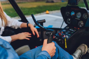 Güneşli bir günde bir helikopter uçuran kadın ve erkek pilotların olduğu bir helikopter görüntüsü..