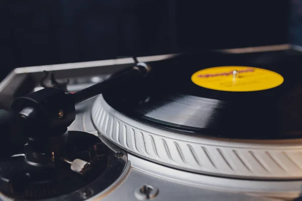 Dj hands on equipment deck and mixer with vinyl record at party.