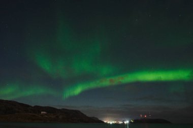 Okyanusun üzerinde Aurora Borealis. Teriberka, Rusya 'nın kuzey ışıkları. Kutup ışıkları ve bulutlarıyla yıldızlı gökyüzü. Aurora 'lı kış manzarası, bulanık sularda taşlı deniz, karlı dağlar. Seyahat