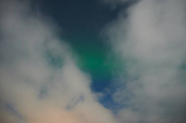 Okyanusun üzerinde Aurora Borealis. Teriberka, Rusya 'nın kuzey ışıkları. Kutup ışıkları ve bulutlarıyla yıldızlı gökyüzü. Aurora 'lı kış manzarası, bulanık sularda taşlı deniz, karlı dağlar. Seyahat