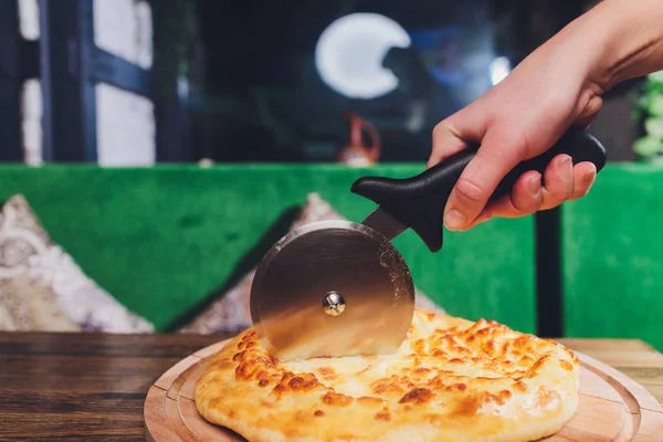 Pizza kesme çarklı, jambonlu pizza, kapsiyum ve masa üzerinde zeytin dilimleri.. — Stok fotoğraf