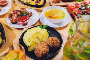 Yemek masasının arka planında patates püresi ve salatalıklı pirzola..