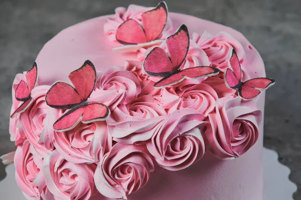 Ogólny widok świeżo upieczone ciasto ozdobione różowym pudrem cukrem, które wyświetlane na tort róże stoją na czarnym tle z lato. — Zdjęcie stockowe