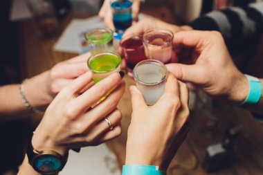 Bokeh arkaplanının önünde kadeh tokuşturup şampanya içen bir grup insanı yakından çek. Yaşlı insanların elleri