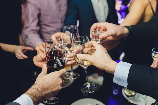 Close up shot of group of people clinking glasses with wine or champagne in front of bokeh background. older people hands — Stock Photo, Image