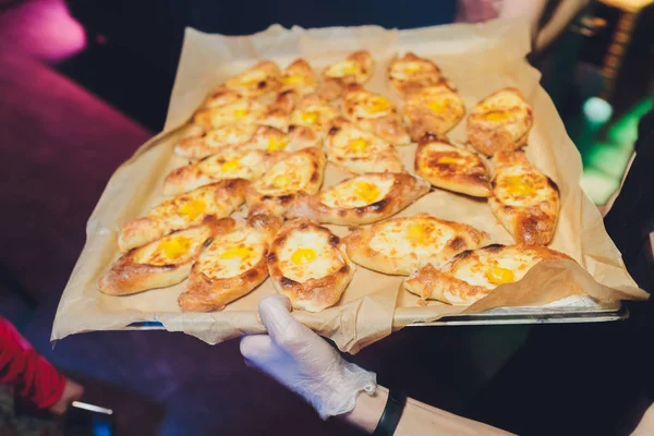 Proceso de cocción de la cocina tradicional adjeariana georgiana y armenia, hachapuri khachapuri con queso suluguni y yema de huevo en una mesa de madera con manos de jefes en el fondo . — Foto de Stock