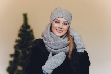 Yana doğru heyecan arayan sürpriz mutlu güzel kadın. Örme sıcak şapka ve gri arka plan üzerinde izole eldivenler giymiş Noel kız.