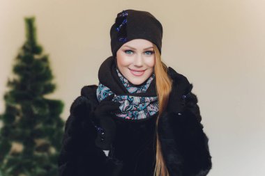 Yana doğru heyecan arayan sürpriz mutlu güzel kadın. Örme sıcak şapka ve gri arka plan üzerinde izole eldivenler giymiş Noel kız.