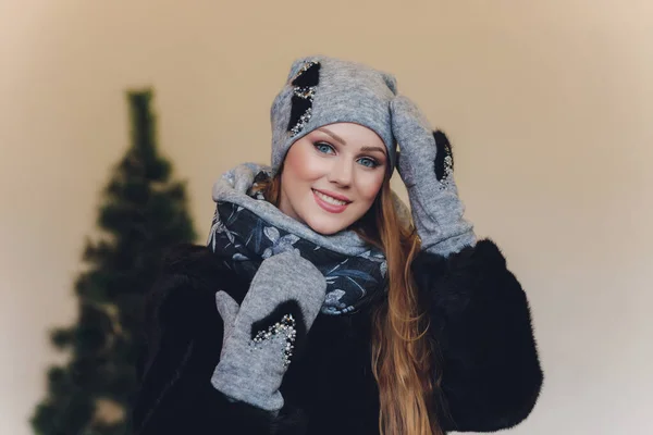 Étonné belle femme heureuse regardant latéralement dans l'excitation. Fille de Noël portant tricot chapeau chaud et mitaines, isolé sur fond gris . — Photo