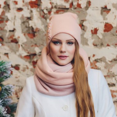 Yana doğru heyecan arayan sürpriz mutlu güzel kadın. Örme sıcak şapka ve gri arka plan üzerinde izole eldivenler giymiş Noel kız.