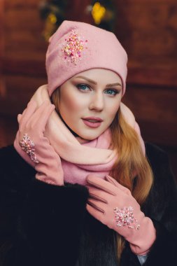 Yana doğru heyecan arayan sürpriz mutlu güzel kadın. Örme sıcak şapka ve gri arka plan üzerinde izole eldivenler giymiş Noel kız.