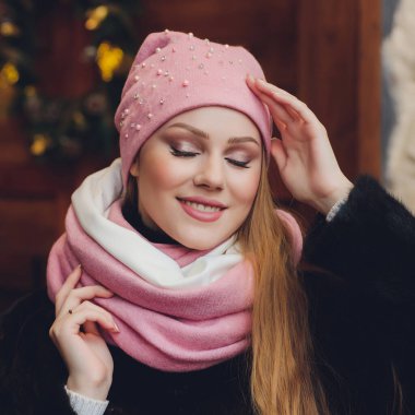 Yana doğru heyecan arayan sürpriz mutlu güzel kadın. Örme sıcak şapka ve gri arka plan üzerinde izole eldivenler giymiş Noel kız.