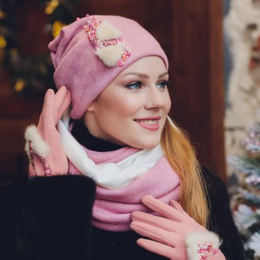 Yana doğru heyecan arayan sürpriz mutlu güzel kadın. Örme sıcak şapka ve gri arka plan üzerinde izole eldivenler giymiş Noel kız.