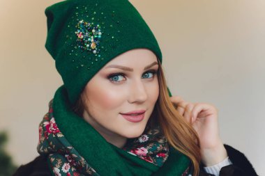 Yana doğru heyecan arayan sürpriz mutlu güzel kadın. Örme sıcak şapka ve gri arka plan üzerinde izole eldivenler giymiş Noel kız.