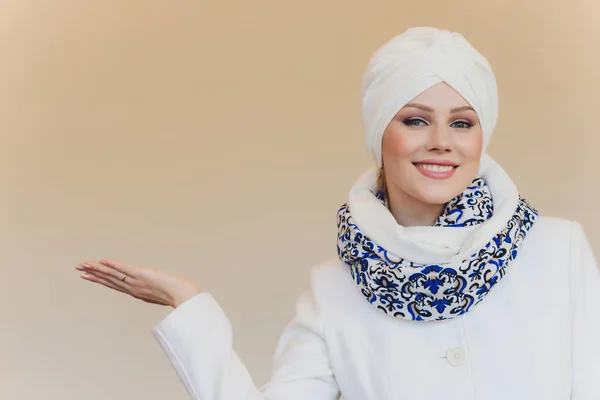 照片中自信的阿拉伯女士头戴头巾，给你指出正确的方向，用双手指向空白，邀请你去那里，推广复制空间。 跟我一起去看看. — 图库照片