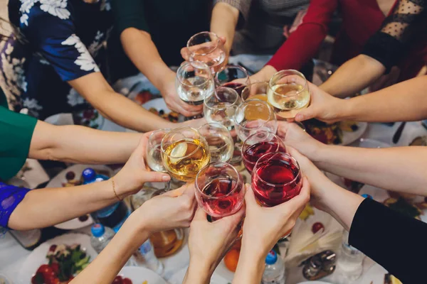 Nahaufnahme einer Gruppe von Menschen, die vor Bokeh-Hintergrund Gläser mit Wein oder Champagner klappern. Ältere Hände. — Stockfoto