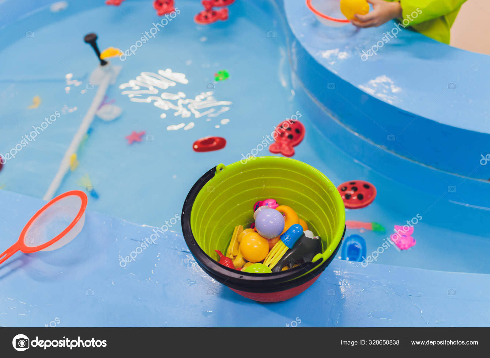 Fishing in the paddling pool. Childrens toys in the pool. Toy fish fishing  rod. Cheerful children fishing, fishing in the paddling pool. — Stock Photo  © vershinin.photo #328650838
