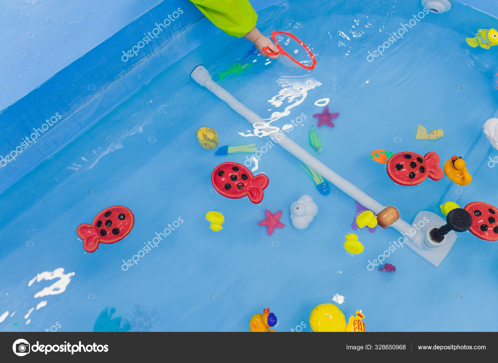 Fishing in the paddling pool. Childrens toys in the pool. Toy fish