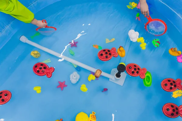 Fiske i paddelpoolen. Leksaker för barn i poolen. Leksaksfiskespö. Glada barn fiske, fiske i paddelpoolen. — Stockfoto