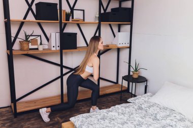Çekici fitness kadını spor salonuna gitmeden sağlıklı bir yaşam tarzının bir parçası olarak evde esneme egzersizleri yapıyor..