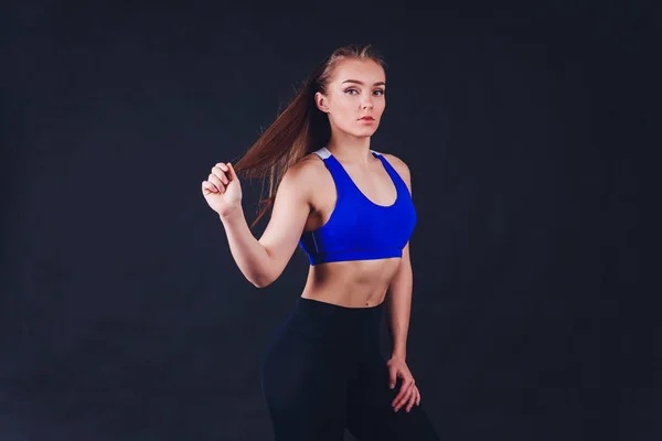 Mladá fitness žena s rukama v rukavicích s pevně sevřeným břišním svalům na černém pozadí s prostorem kopírování svalnatá žena s dlouhými blond vlasy a ABS fitness lid. — Stock fotografie