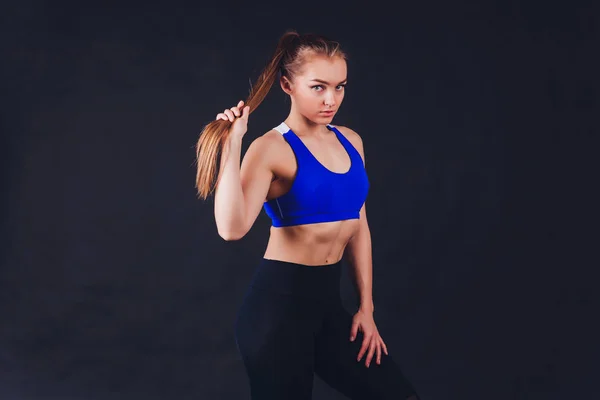 Mladá fitness žena s rukama v rukavicích s pevně sevřeným břišním svalům na černém pozadí s prostorem kopírování svalnatá žena s dlouhými blond vlasy a ABS fitness lid. — Stock fotografie