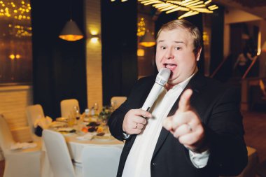 Akşamki konserde sahne ışıkları altında gri bir takım elbiseyle performans sergileyen yakışıklı genç adam..