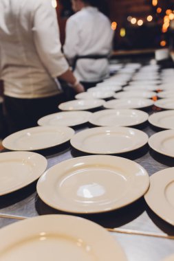 Masada bir sürü beyaz seramik porselen kap tabağı var. Çömlek arkaplanı.