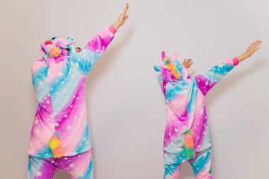 Tek boynuzlu at kigurumi kostümü giyen bir kız. Kostüme ya da pijama partisine hazırlanıyor. Beyaz arka planda poz verirken kameraya bakan pijamalı genç bayan..