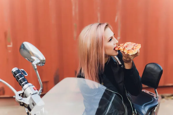 Girl eating a delicious pizza while sitting on a motorcycle. — 스톡 사진
